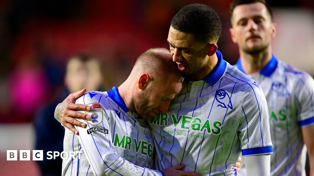 Former Sheffield Wednesday captain Barry Bannan, wearing the club's away shirt of white with royal blue collar and vertical pinstripes, is comforted by team-mate Liam Palmer after a game