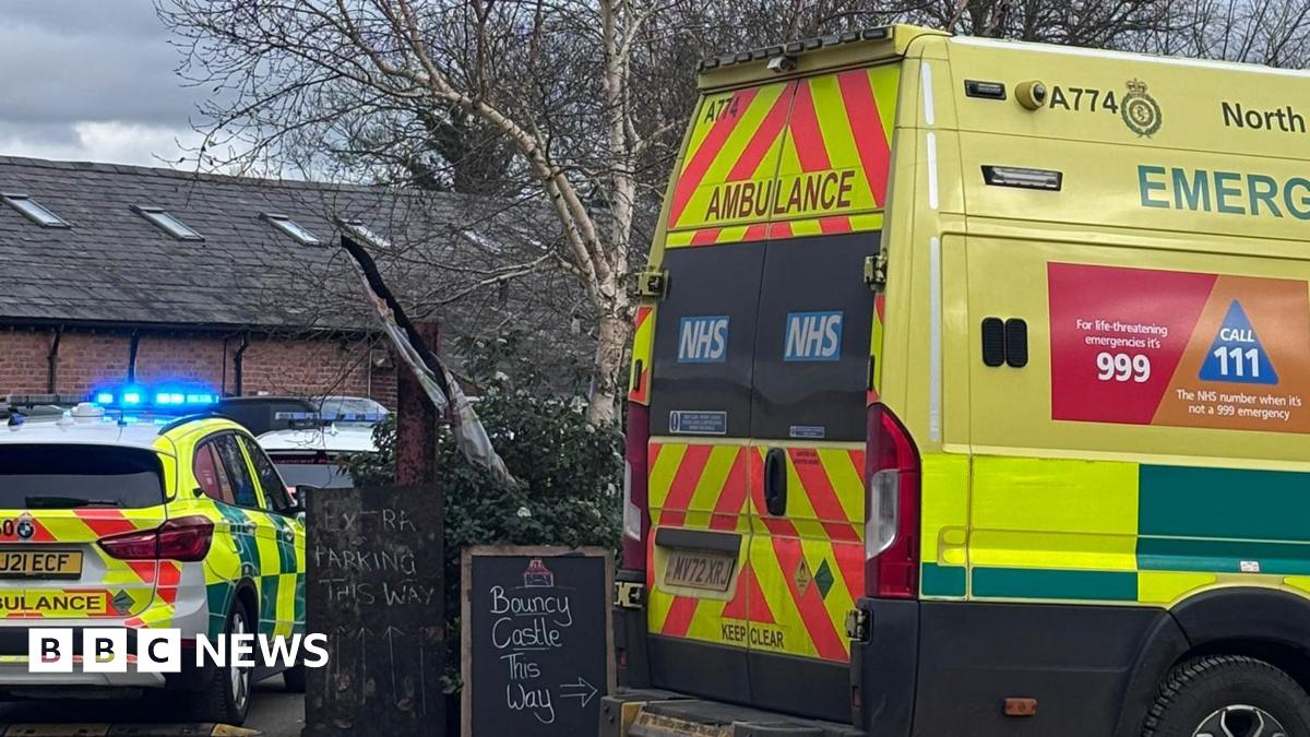 An ambulance and ambulance response vehicle are parked at the farm. A sign says 'bouncy castle this way' while another says 'parking this way'.