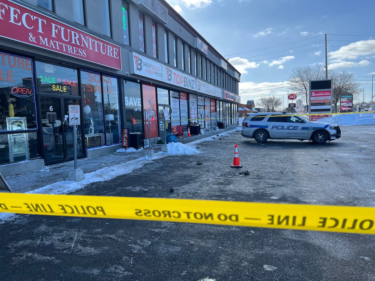 Plaza area blocked off by police tape, police car in the background