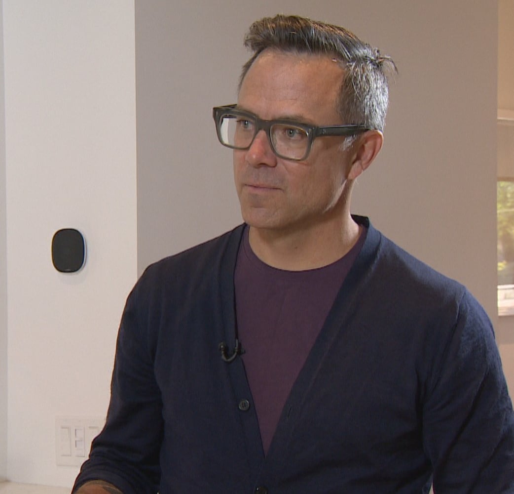 A man with glasses standing by a door. 