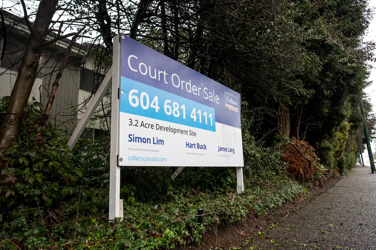 A real estate billboard advertising a court-ordered sale is posted at a condo building