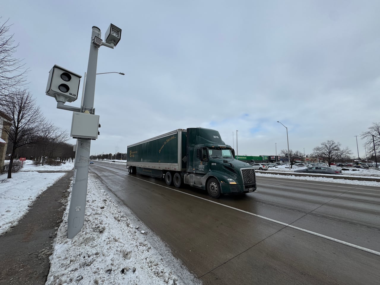 red light camera on a pole with a transport truck on the road