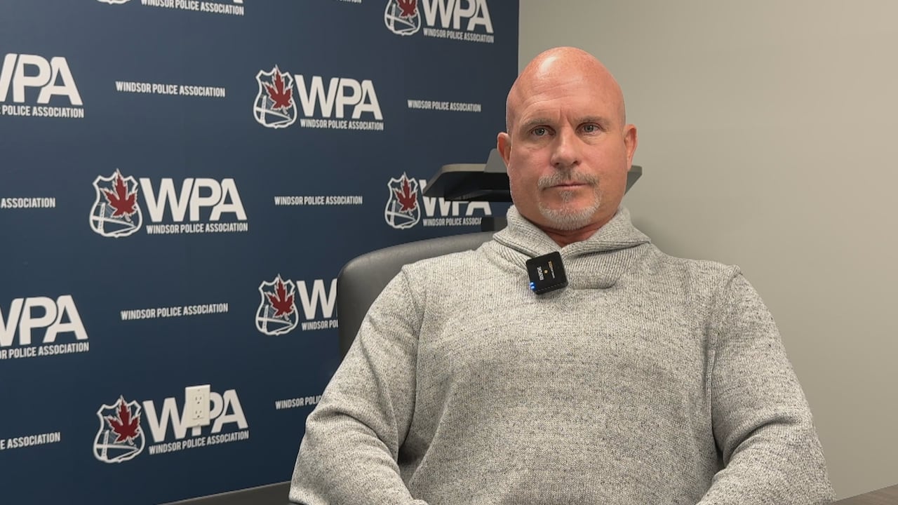 Kent Rice sits in front of a blue Windsor Police Association banner