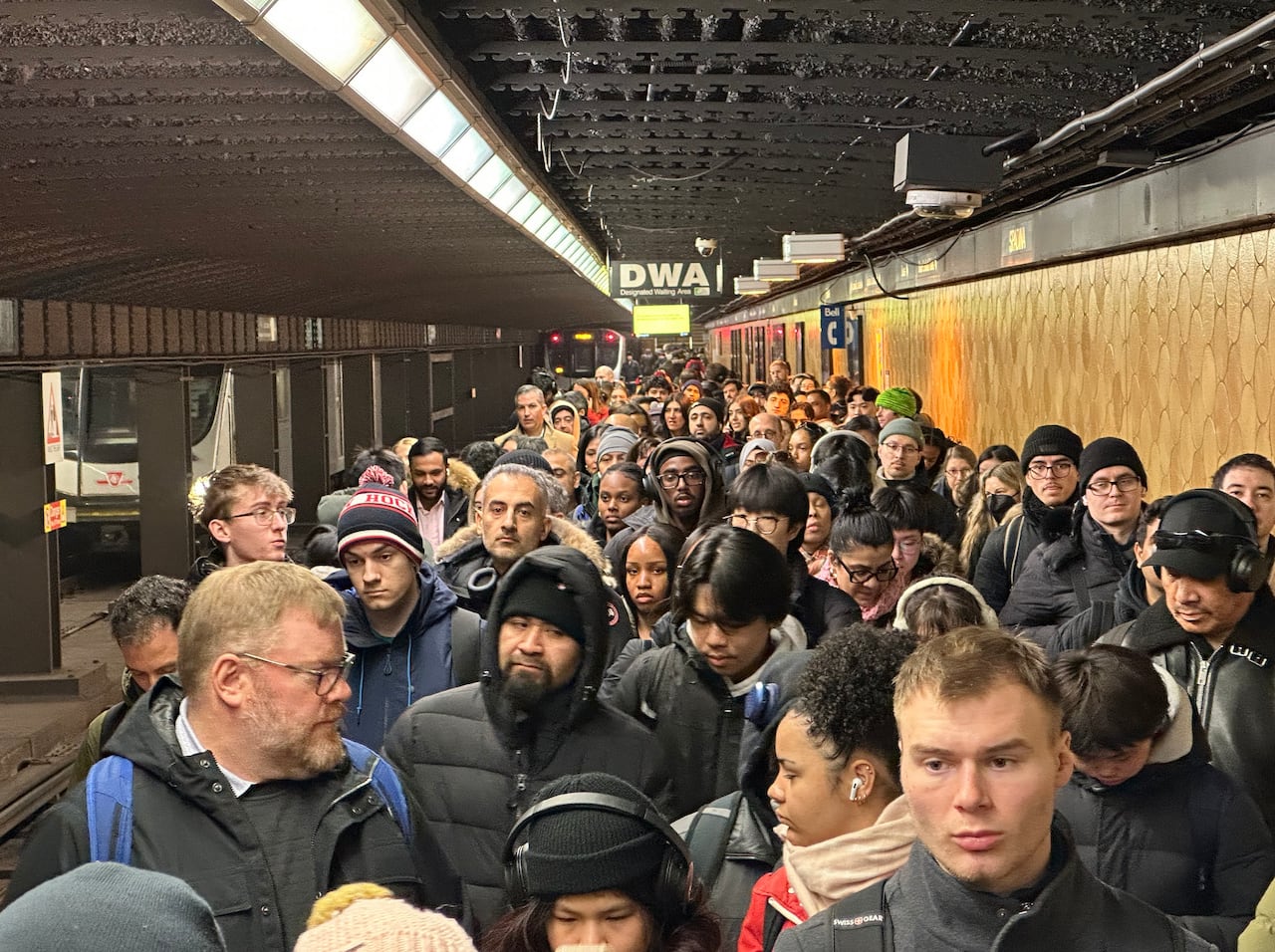 A crowded subway platform in Toronto, with commuters packed elbow to elbow