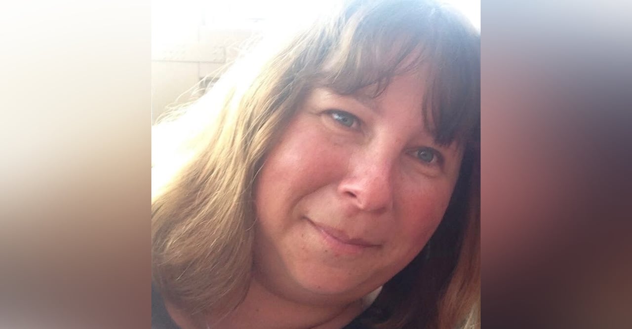 Woman with long light hair and bangs and blue eyes smiles