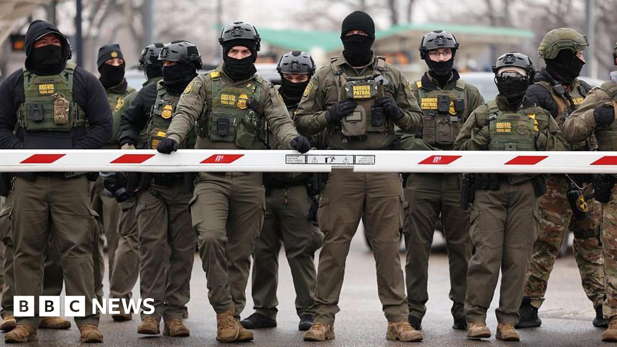 US immigration enforcement officers stand in line behind a barrier in Minnesota in January