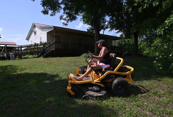 Marie Jackson mows her lawn, Thursday, May 8, 2025, in Resaca, Ga. She spent her childhood playing and swimming in the Conasauga River, downstream from Dalton. Her idyllic memories are overshadowed by recollections of foam on the river and dead fish. (Hyosub Shin/Atlanta Journal-Constitution via AP)
