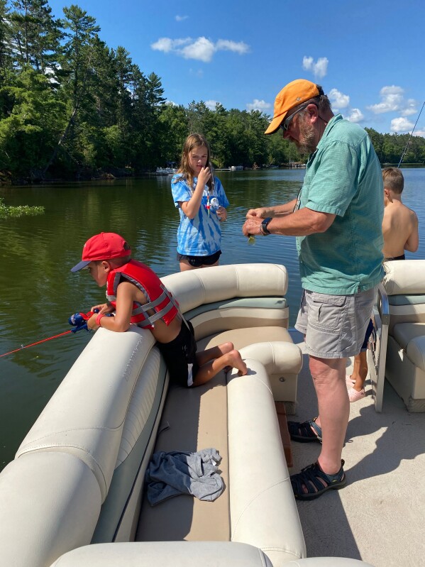 Tom LaDue baits a hook with his grandkids in 2022 before PFAS contamination was discovered in Snowden Lake in Stella, Wis. (Courtesy Tom LaDue via AP)