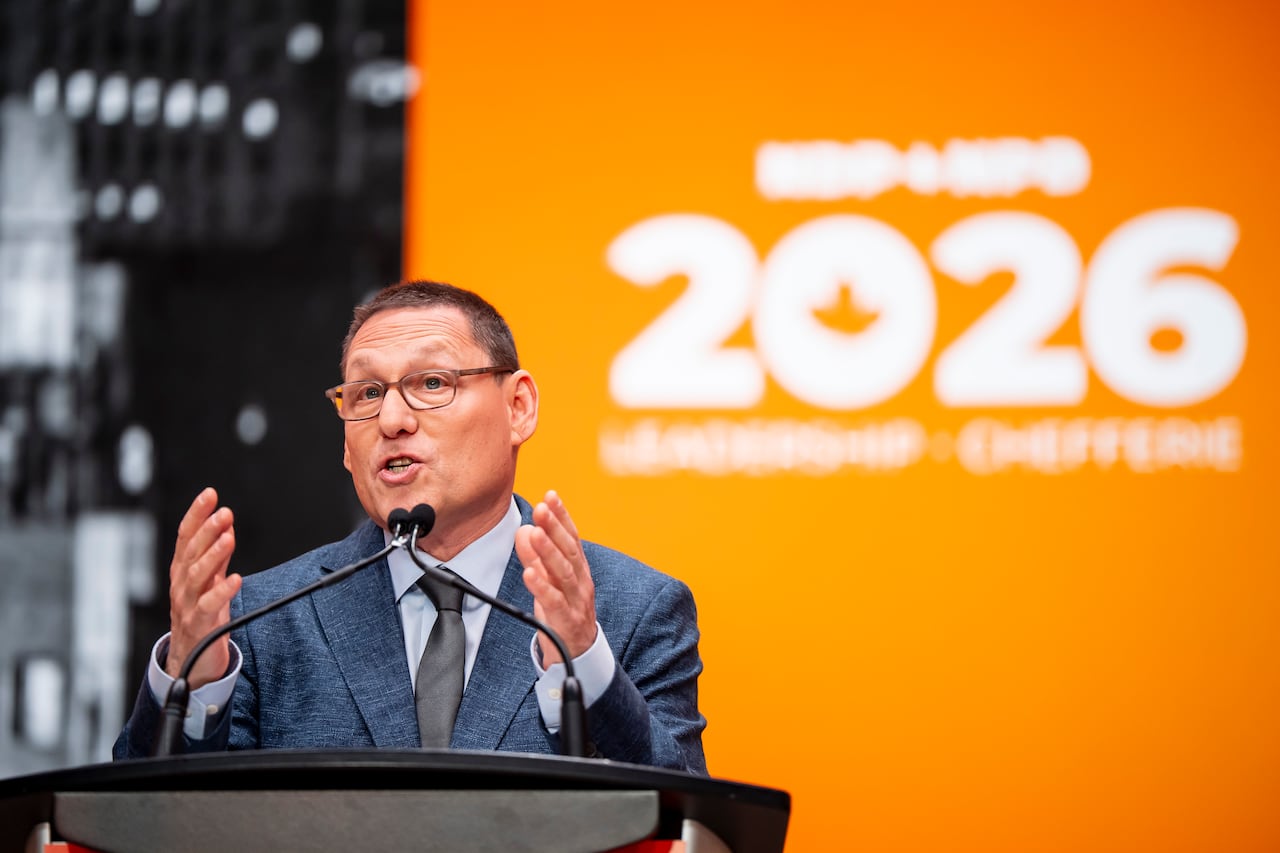 A man in a blue suit stands at a podium