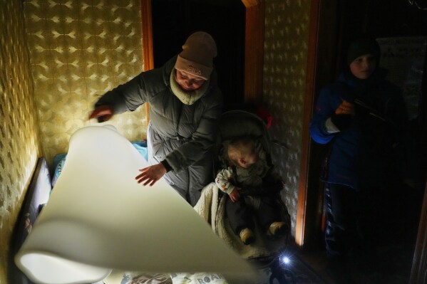 Yuliia Dolotova, 37, uses foam rubber to insulate her children’s bed in her apartment during a power outage caused by Russia’s repeated air strikes on the country’s power grid, in Kyiv, Ukraine, Monday, Feb. 2, 2026. (AP Photo/Sergey Grits)