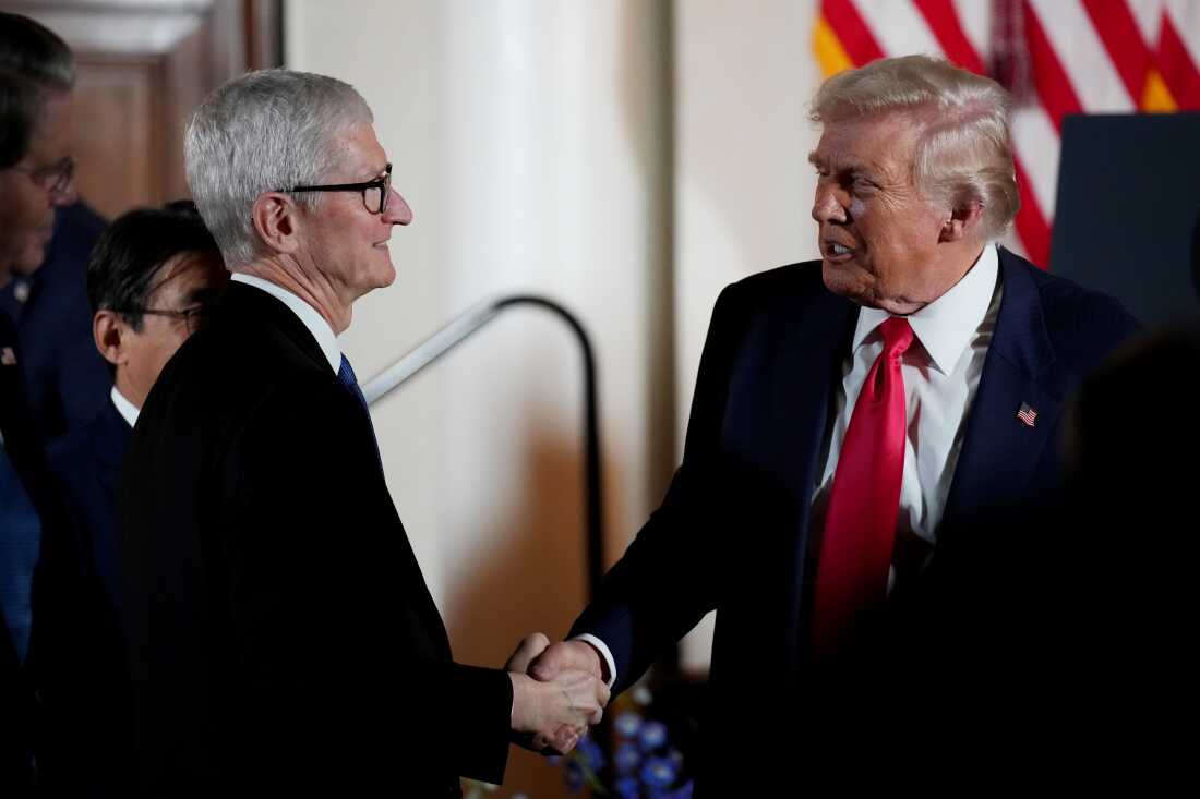President Trump shakes hands with Apple CEO Tim Cook during a meeting with business leaders in Tokyo in October. Both men are wearing suits, and Cook is standing on the left side of the frame.