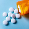 White round pills in orange bottle on blue background banner close up with copy space