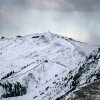 This photo of Colorado's Arapahoe Basin ski area shows early season snow on peaks. Also seen on the peaks are some structures, fences and conifer trees.
