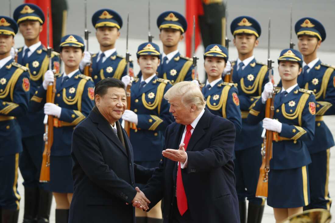 President Trump and Chinese President Xi Jinping shake hands at a welcoming ceremony on November 9, 2017, in Beijing. Two rows of military personnel wearing uniforms and carrying rifles with bayonets stand in the background.