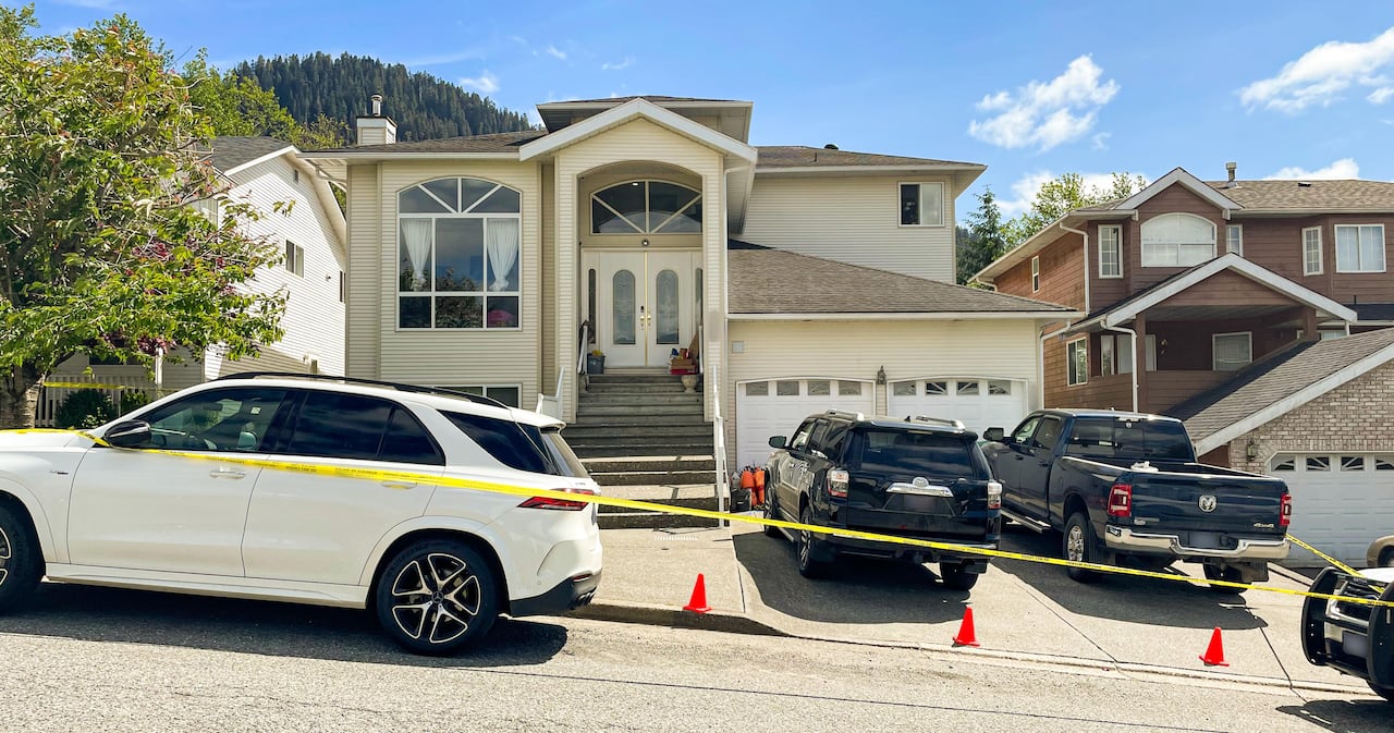 A large family home with a two-car garage is surrounded by police tape. 