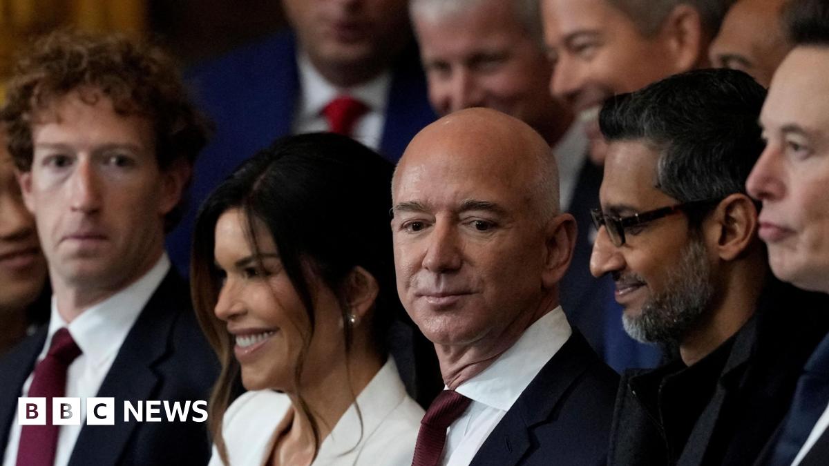 Mark Zuckerberg and Jeff Bezos wearing similar navy suits, with white dress shirts and dark red ties at the second inauguration of Donald Trump. Sundar Pichai and Elon Musk are next to them, both dressed in black.