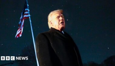 US President Donald Trump responds to a question from the news media as he walks to board Marine One on the South Lawn of the White House. An American flag is visible behind him.