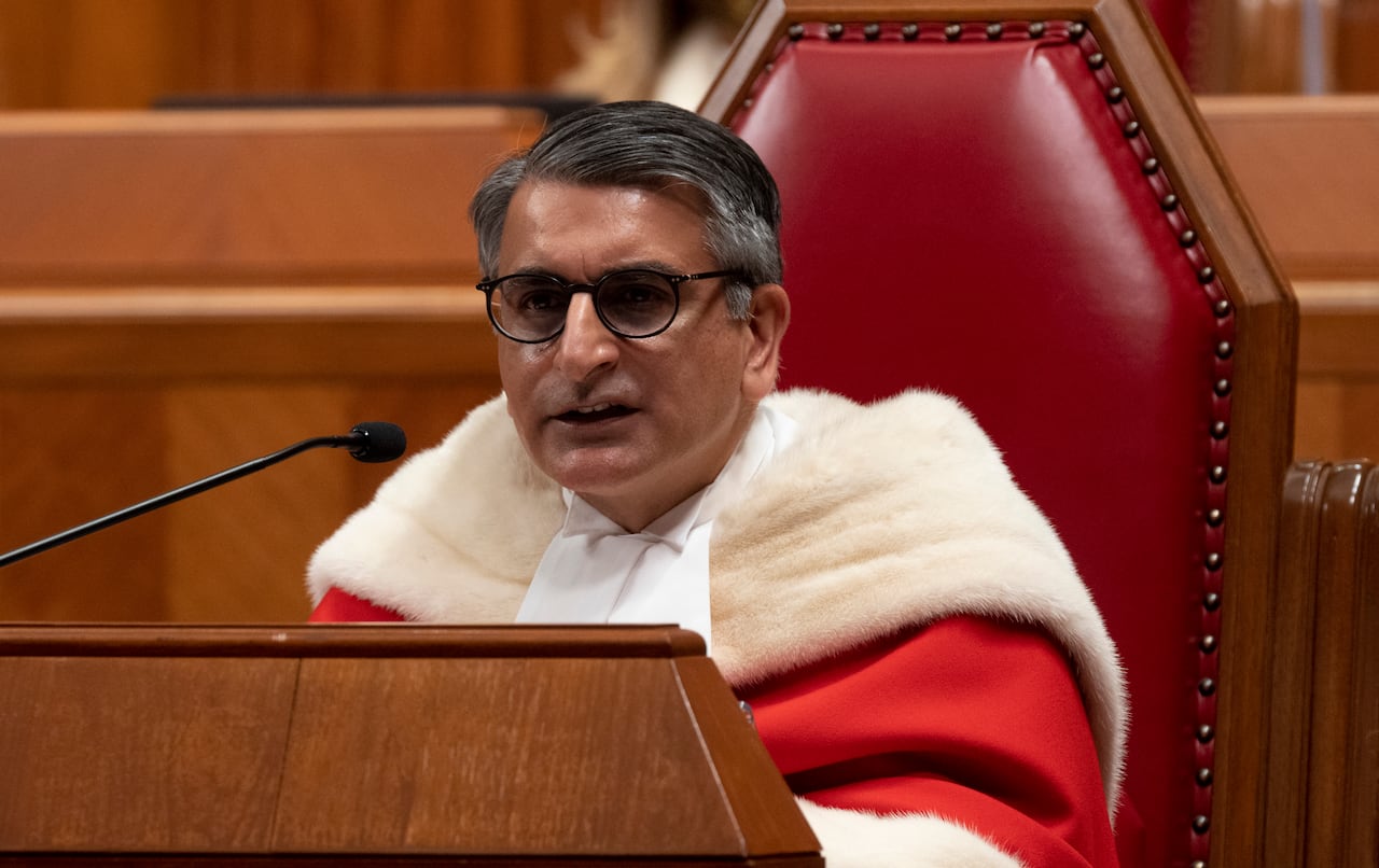 A man in a red judges robe speaks into a microphone.