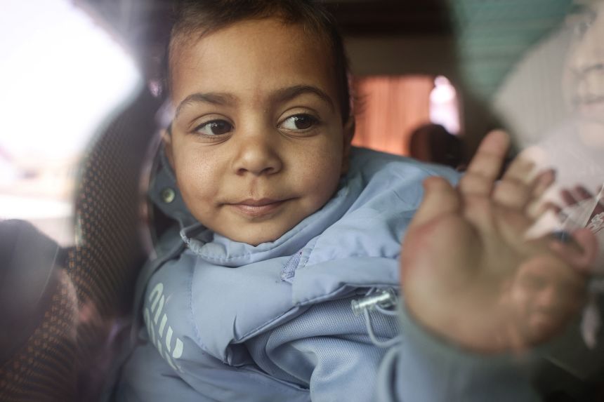 A Palestinian child waves from the window of a bus evacuating war-wounded patients through the Rafah border crossing between Gaza and Egypt on Monday.