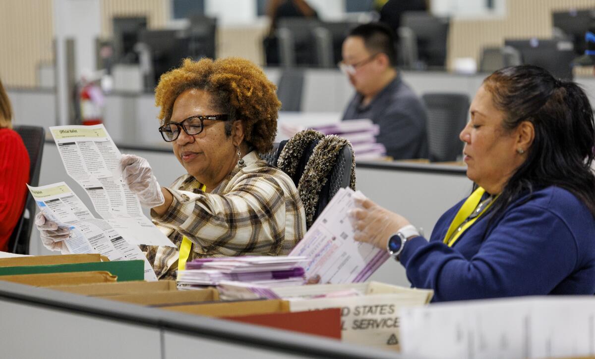 Election workers inspect ballots after extracting them from envelopes.