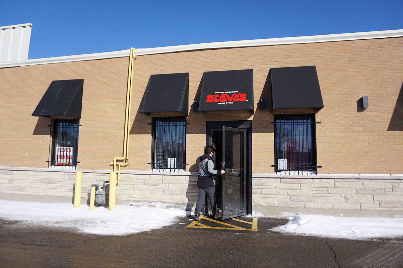a man with a black and grey jacket going inside a store.