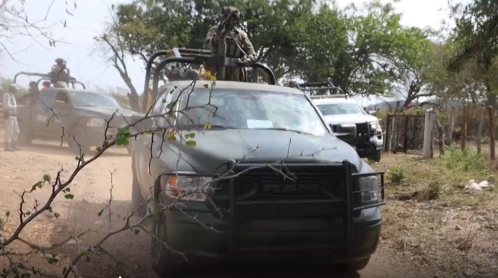 Soldiers with guns on pickup trucks.