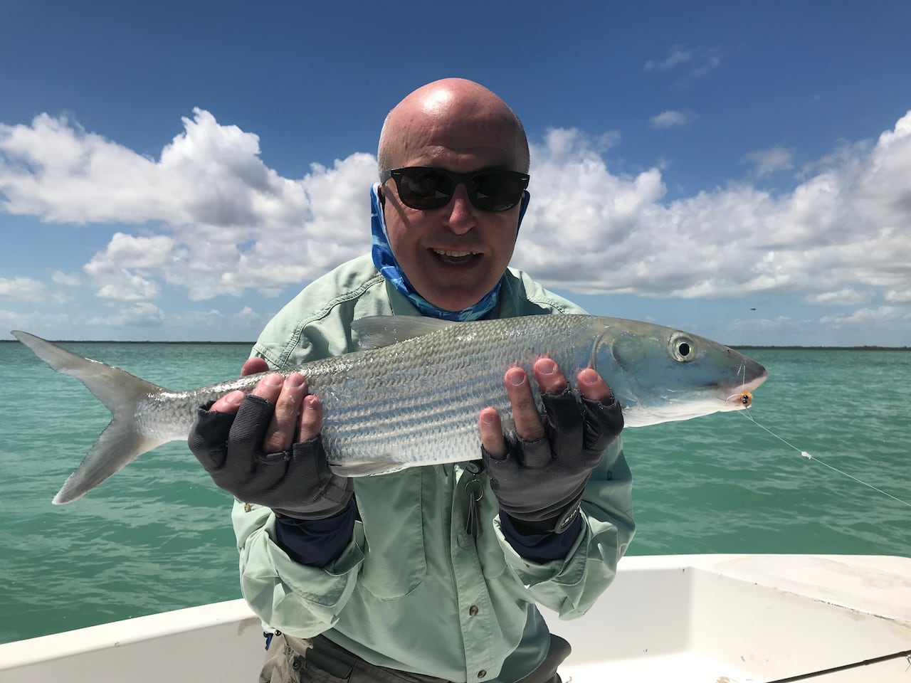 A smiling man on a boat holds up a big fish