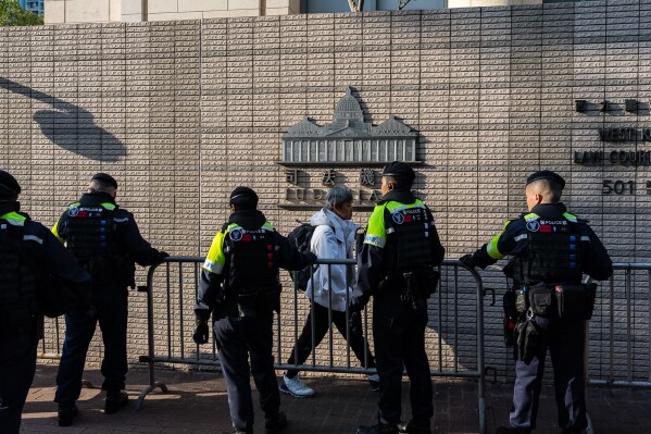 Police officers stand guard outside the West Kowloon Magistrates' Courts ahead of the sentencing of Jimmy Lai on Monday. (AP Photo/Chan Long Hei)