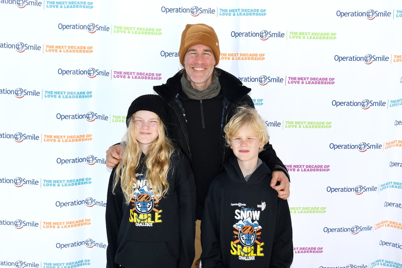 blond man stands with arms around two blond kids