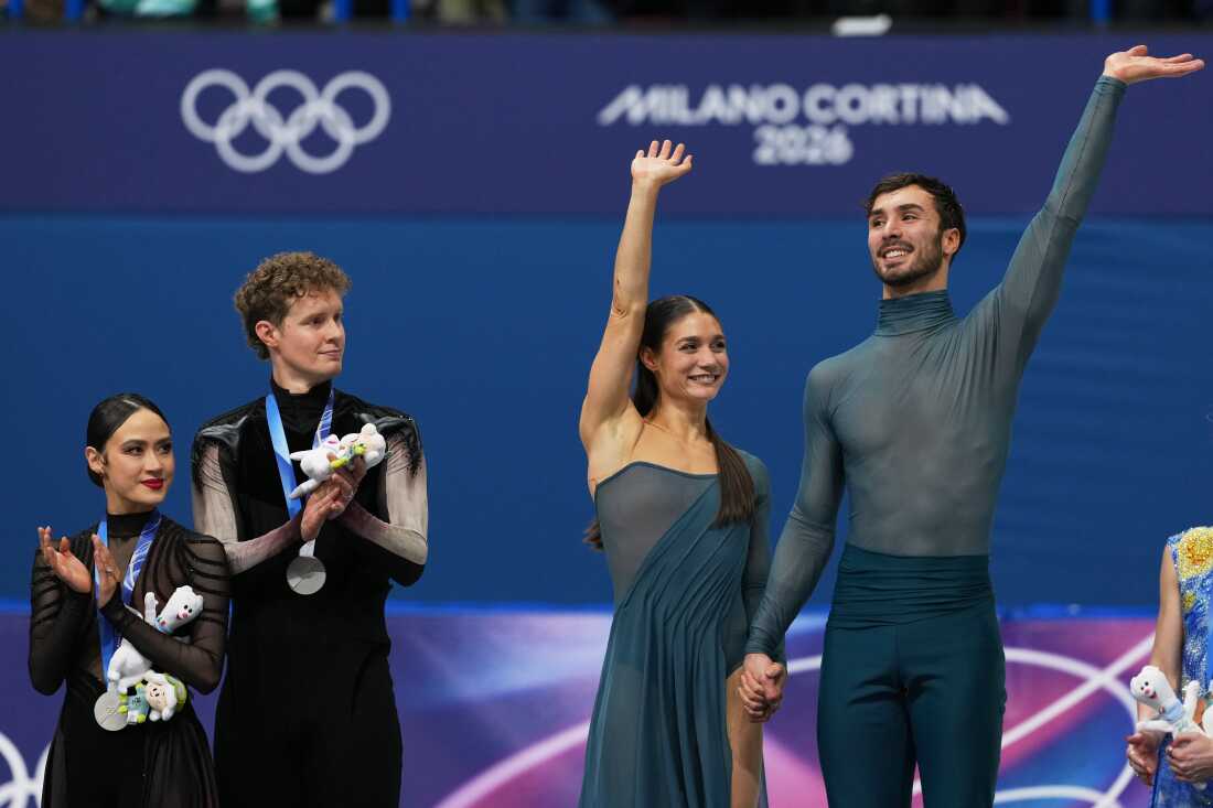 Gold medalists Laurence Fournier Beaudry and Guillaume Cizeron of France wave to the crowd in Milan as silver medalists Madison Chock and Evan Bates of the U.S. look on.