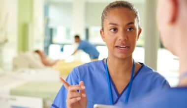 Nursing staff talking with a nurse speaking to a patient in bed in the background