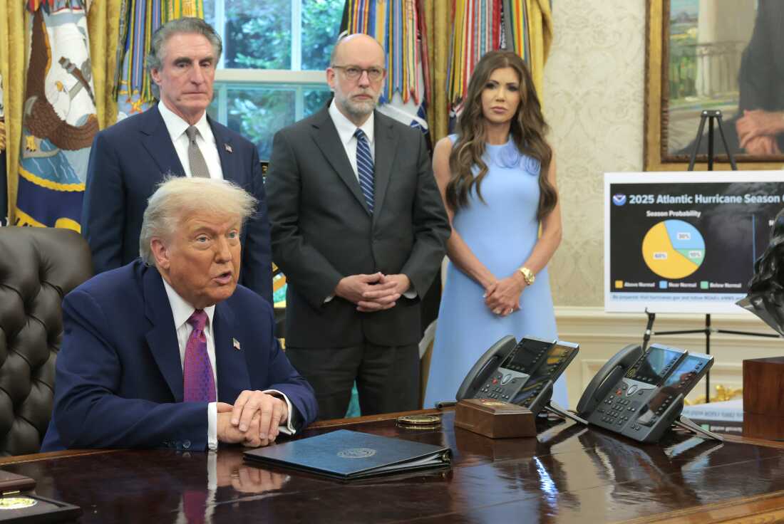 President Trump is pictured at the Resolute Desk with OMB Director Russell Vought, Homeland Security Sec. Kristi Noem and Interior Sec. Doug Burgum standing behind him.