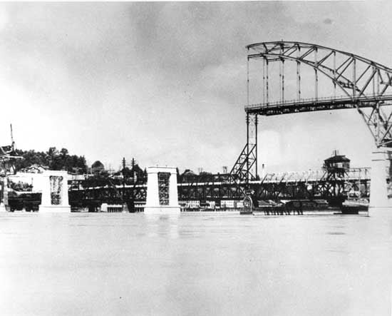 A historical photo of the Pattullo Bridge under construction. Half of the centre span is up.
