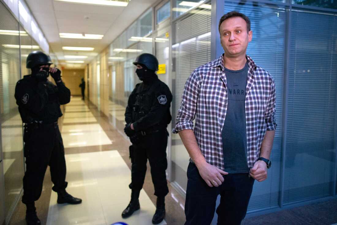 FILE - Russian opposition leader Alexei Navalny speaks to the media in front of security officers standing guard at the Foundation for Fighting Corruption office in Moscow, Russia, Thursday, Dec. 26, 2019.