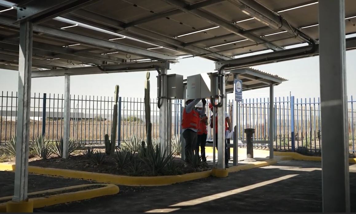  Three people siloutted beneath a solar panel complex