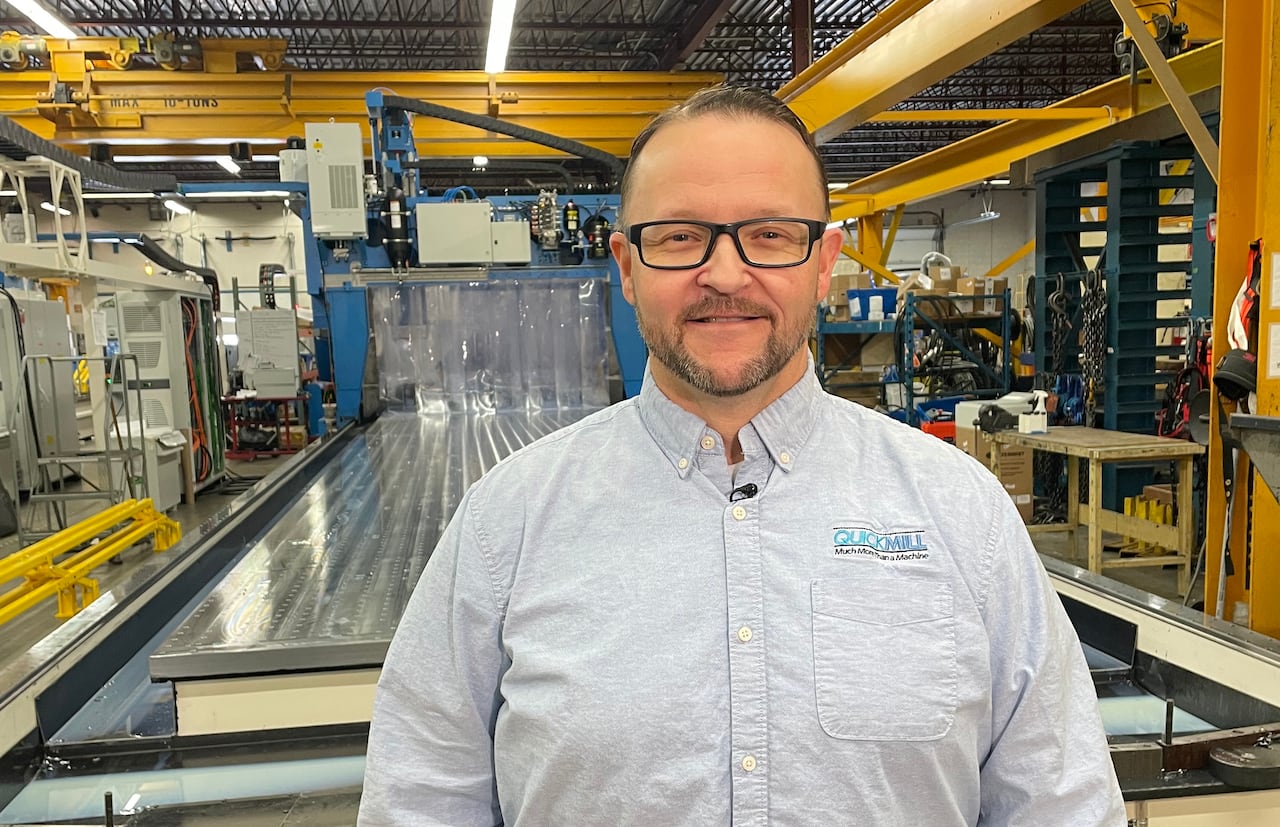 A man standing in front of machinery indoors.