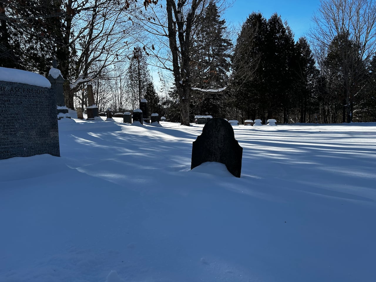 A tombstone in a snowy graveyard