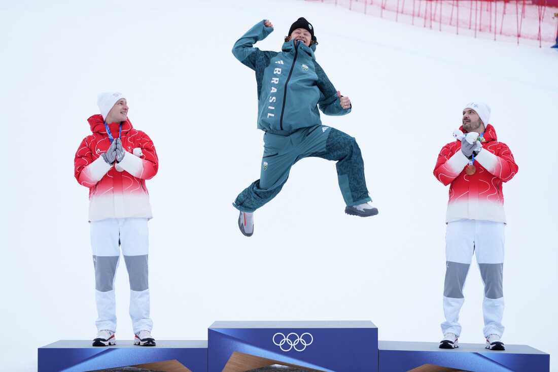 Brazil's Lucas Pinheiro Braathen, center, celebrates winning a gold medal for an alpine ski, men's giant slalom race, as silver medalist Switzerland's Marco Odermatt, right, and bronze medalist Switzerland's Loic Meillard applaud, at the 2026 Winter Olympics, in Bormio, Italy, Saturday, Feb. 14, 2026.