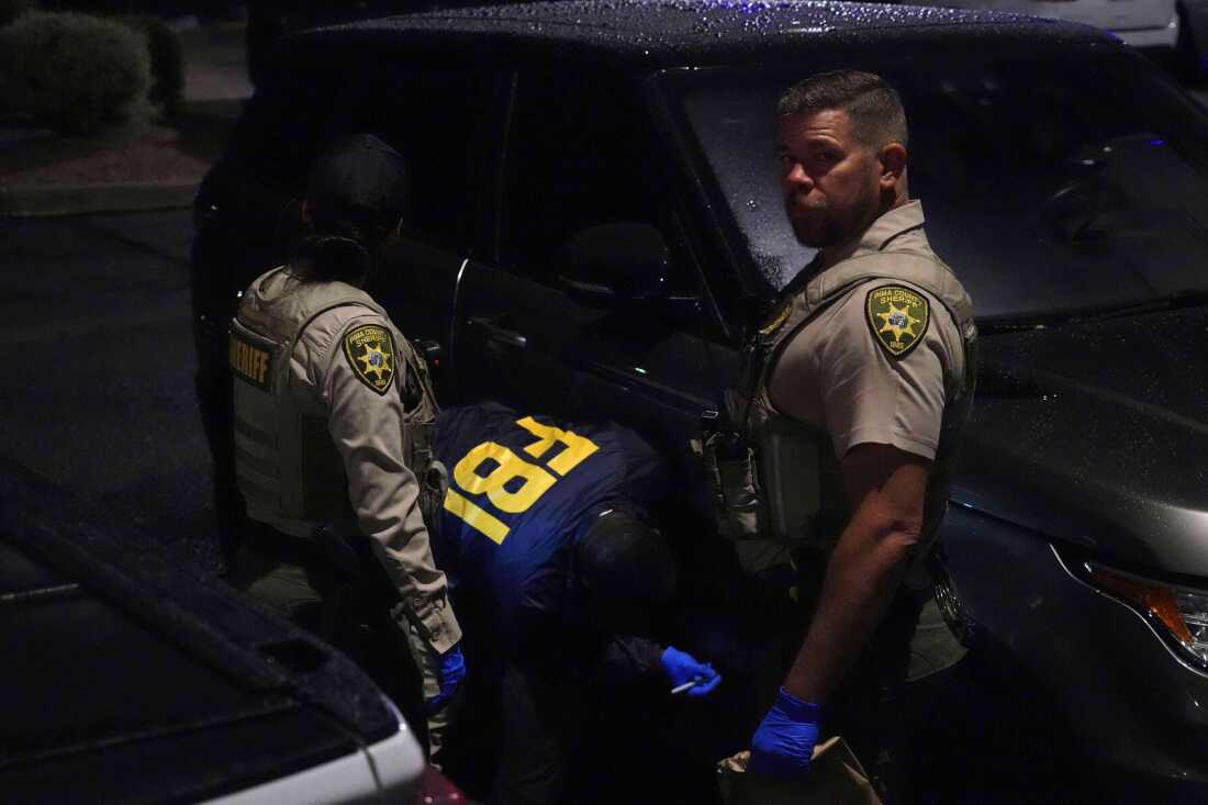 Law enforcement from the Pima County Sheriff's Department and the FBI work on a Range Rover in a Culver’s parking lot in Tucson, Ariz., early Saturday.