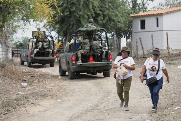 Members of a group that searches for missing people walk alongside soldiers in El Verde, Sinaloa state, Mexico, Monday, Feb. 8, 2026. (AP Photo/Juvencio Villanueva)