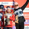 Three female skiers wearing winter gear hold trophies.