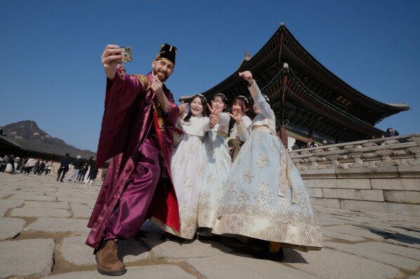 People wearing South Korean traditional "Hanbok" costume take photos on the eve of the Lunar New Year at the Gyeongbok Palace, the main royal palace during the Joseon Dynasty, in Seoul, South Korea, Monday, Feb. 16, 2026. (AP Photo/Ahn Young-joon)