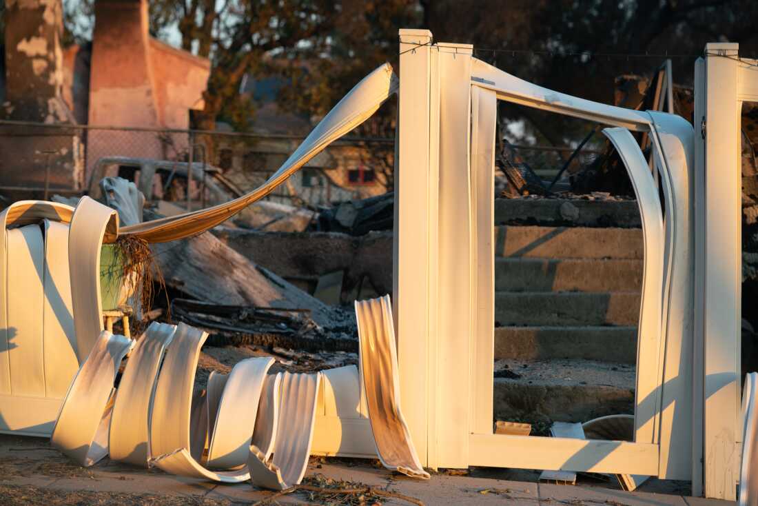 A part of a melted fence spills over a yard in Altadena, Calif., after the Eaton Fire devastated the neighborhood in 2025.