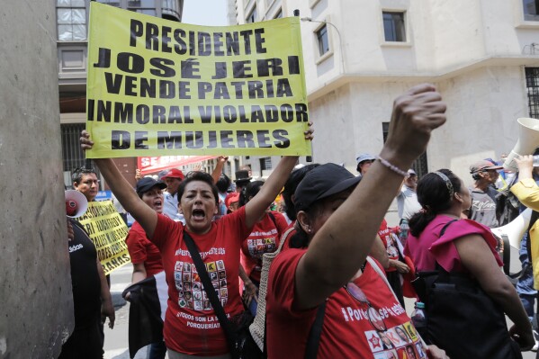People protest against Peruvian President Jose Jeri outside the location where lawmakers are debating his removal in Lima, Peru, Tuesday, Feb. 17, 2026. The sign reads in Spanish "President Jose Jeri, traitor, immoral, rapist of women," referring to a rape accusation case against the president that was dismissed by the prosecutor's office in August 2025. (AP Photo/Gerardo Marin)