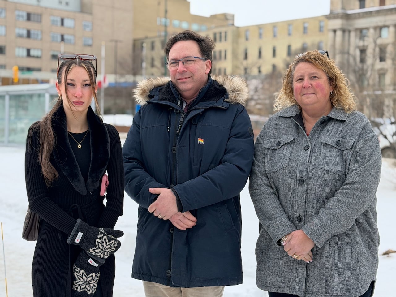 Two women and a man stand outside a hospital.