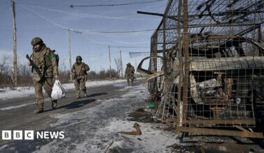 Negotiators sit around tables in a panelled room, with the flags of Russia, the US, Switzerland and Ukraine at the back.