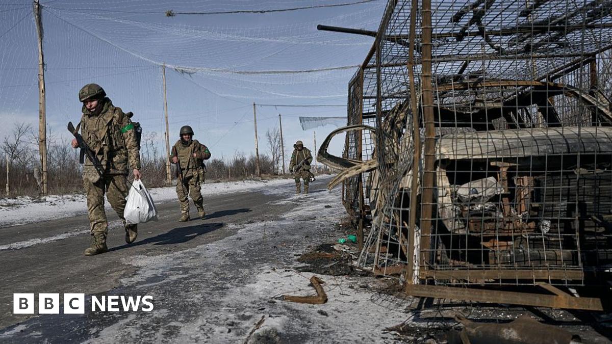 Negotiators sit around tables in a panelled room, with the flags of Russia, the US, Switzerland and Ukraine at the back.