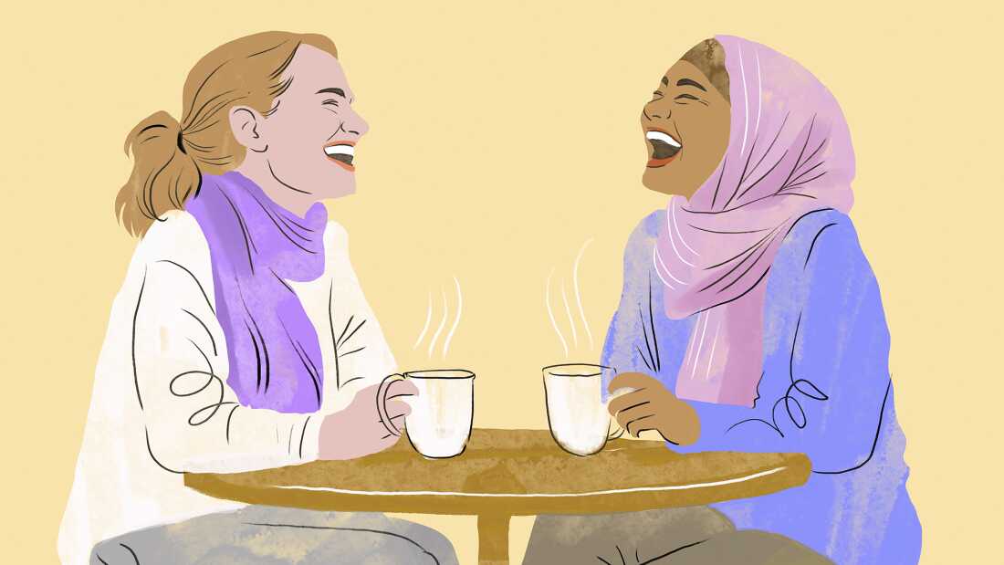 An illustration in a style mixing line drawing with pastel, shows two women laughing and talking over coffee at a cafe. The woman on the left has white skin, a sandy blonde ponytail, and wears a purple neck scarf and white sweater. The woman on the right has light brown skin, and wears a pink headscarf and a purple sweater. Both women hold white mugs with steam coming out of them and throw their heads back in laughter. They are set against a light yellow background.