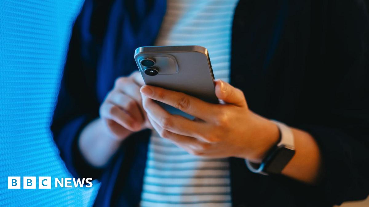 A young woman holds a smartphone in her hands.