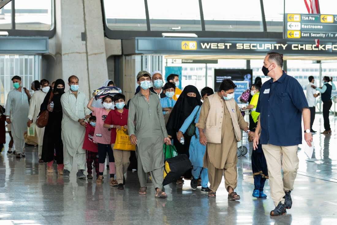 Refugees walk through the departure terminal to a bus at Dulles International Airport after being evacuated from Kabul following the Taliban takeover of Afghanistan in August 2021 in Dulles, Va.
